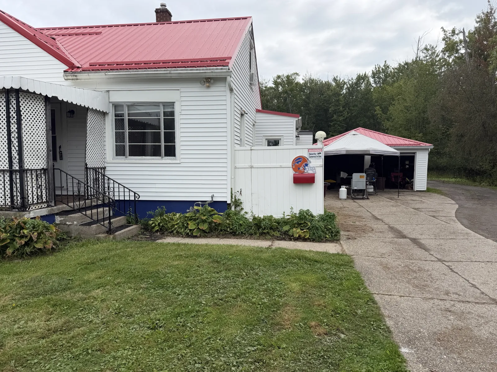 The driveway side of the house, with a canopy over grills and propane tanks by the garage.